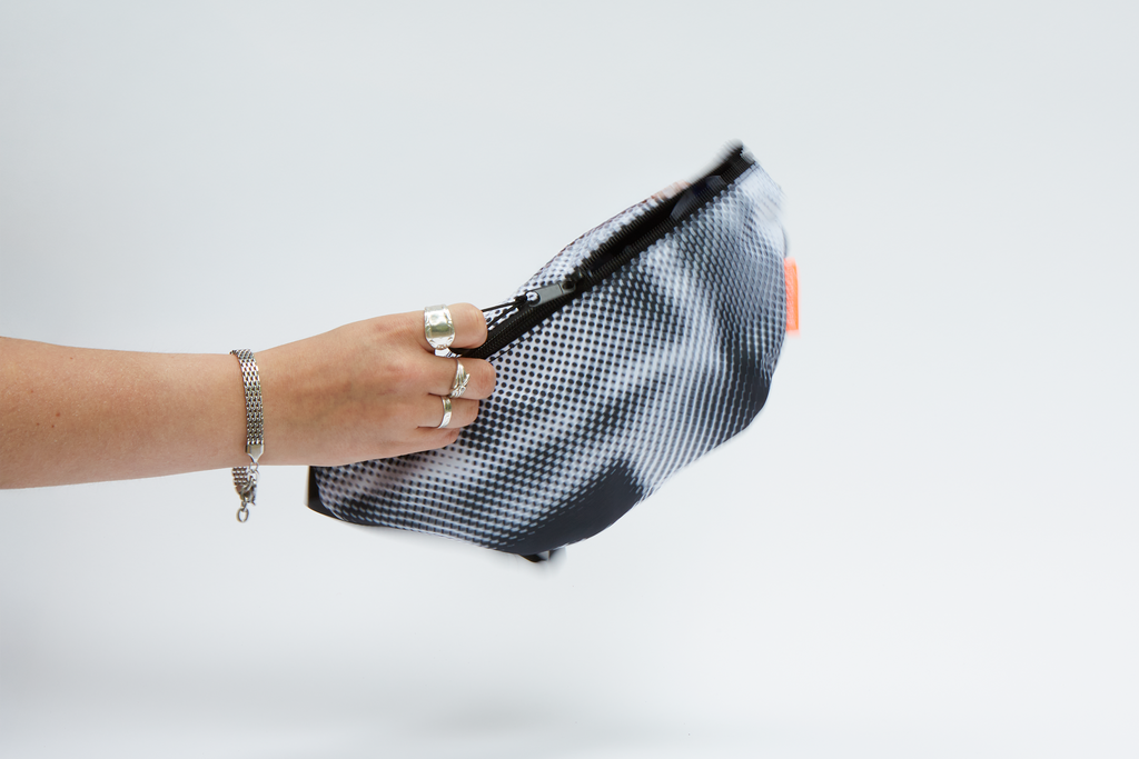Eine Hand zieht den Reißverschluss der Hipbag auf