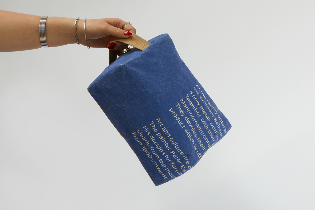 Eine Hand hält die Kulturtasche am Tragegriff