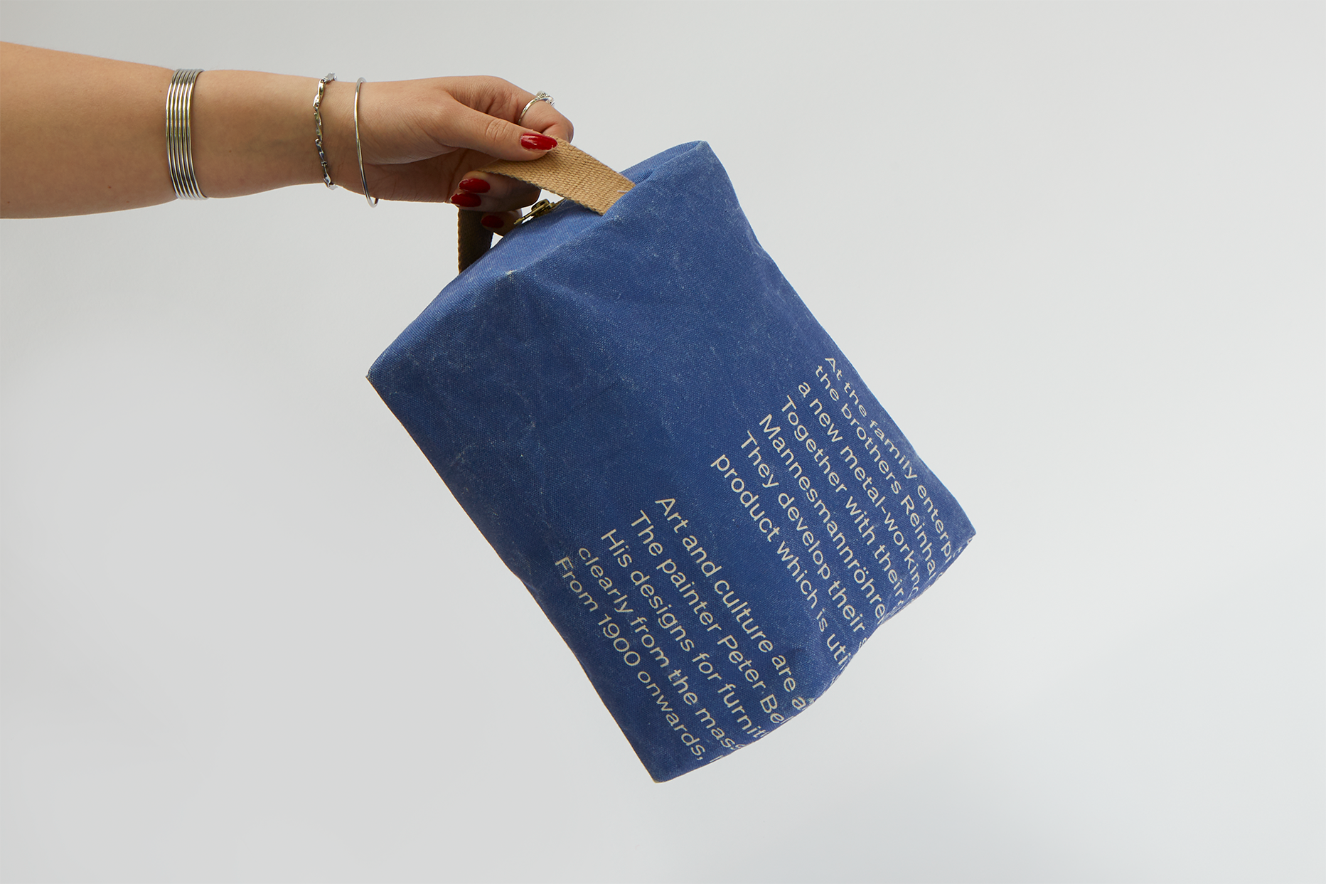 Eine Hand hält die Kulturtasche am Tragegriff