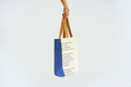 Eine von oben ins Bild hineinragende Hand hält die hängende Totebag